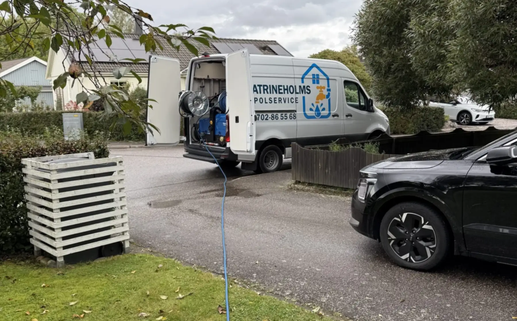 Spolslangen dragen över gräsmattan från servicebilen till en villa